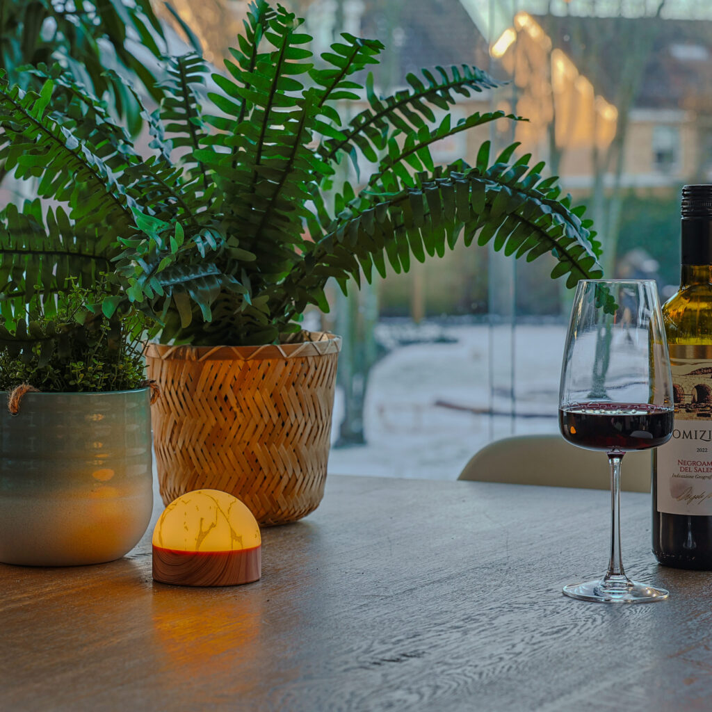 mooie tafellamp van dorsetto oplaadbaar brandtijd 105 uur en waterdicht geel met marmer look op tafel bij wijnglas en planten