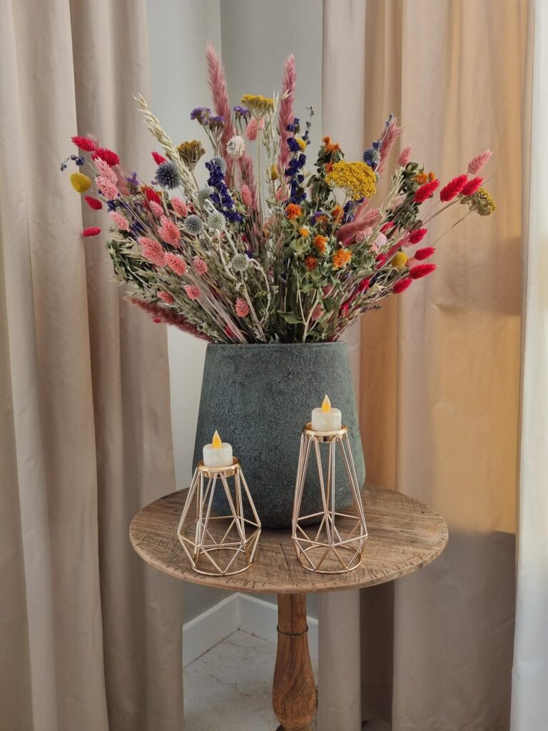 theelichtjes in een metalen houder op een tafeltje met bloemen in een pot